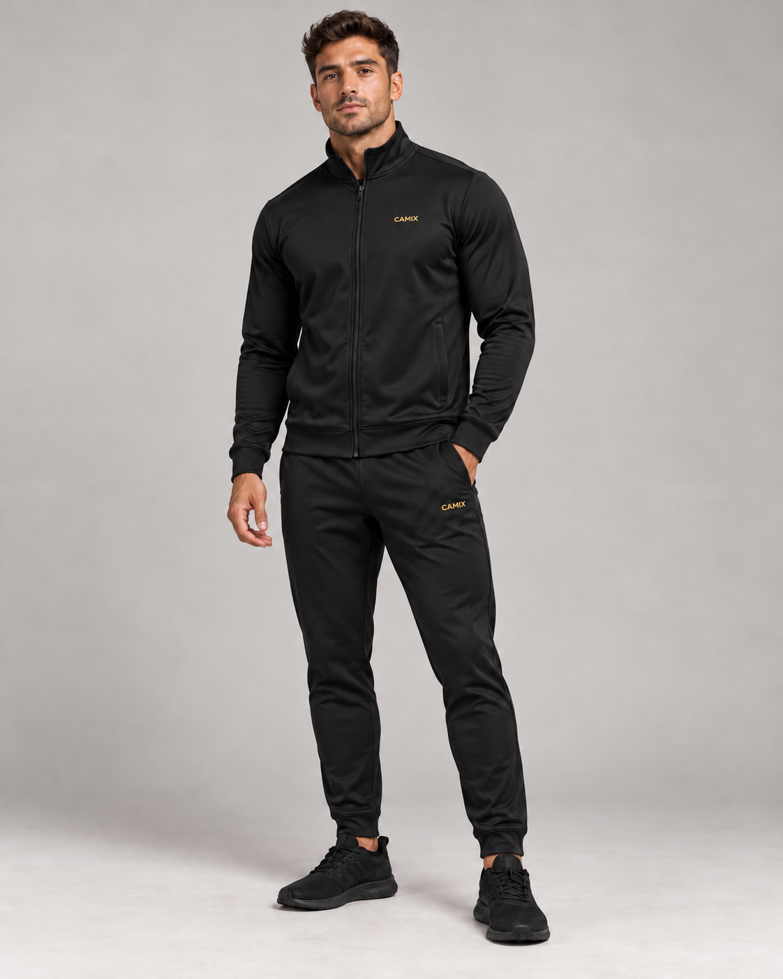 CAMIX Performance Trainingspak voor heren in zwart met gouden logo, schuin vooraanzicht